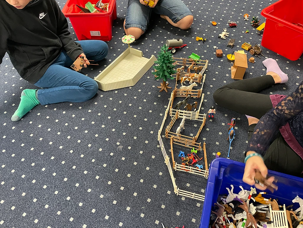 Die Kinder spielen mit Bauernhof-Figuren.