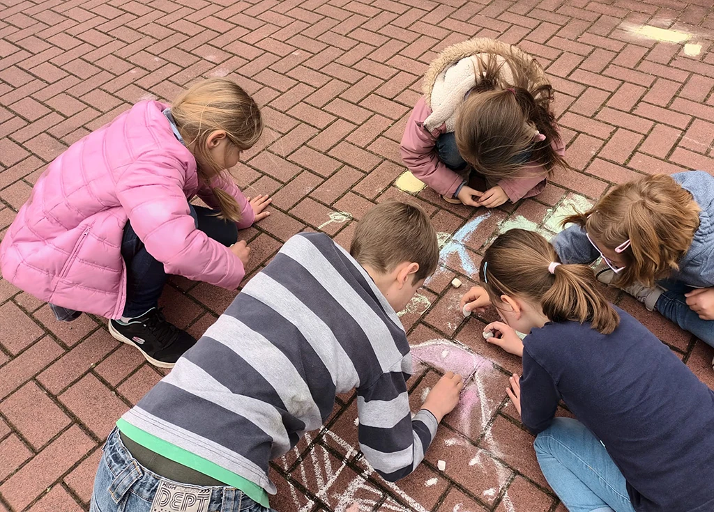Kinder malen mit Kreide auf dem Boden