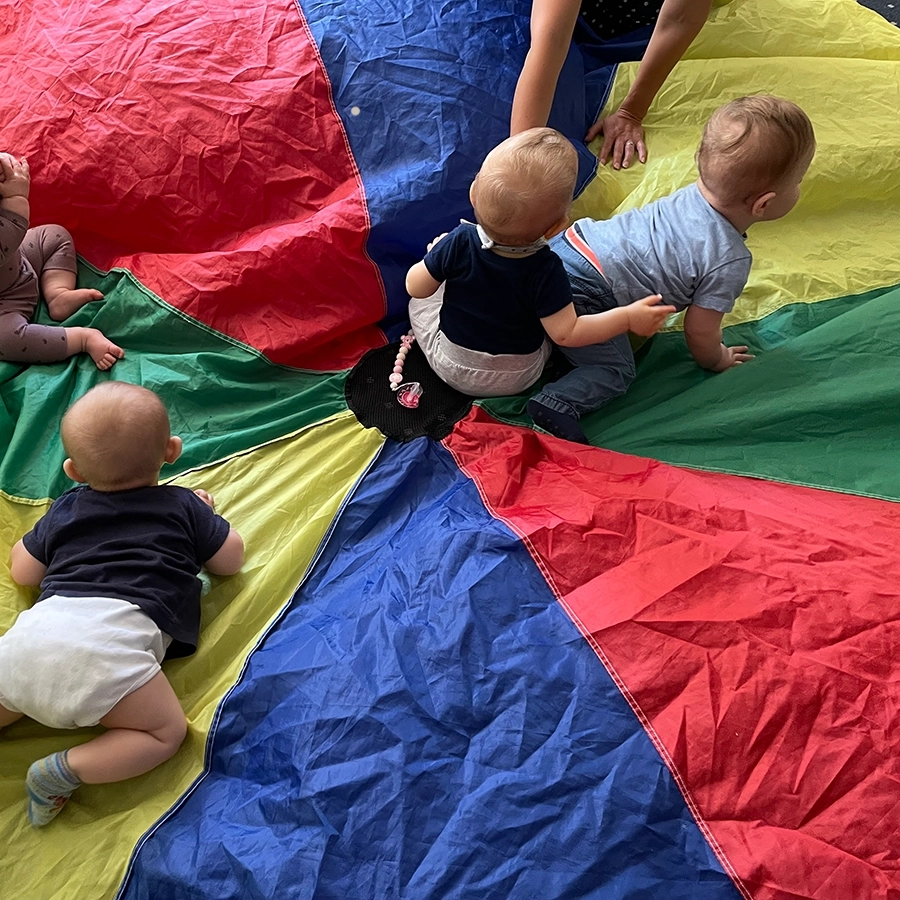 Die Babys krabbeln auf dem bunten Schwungtuch.
