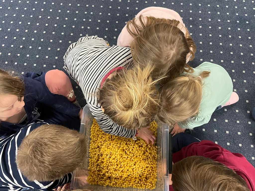 Die Kinder wühlen in einer Kiste mit Nudeln.