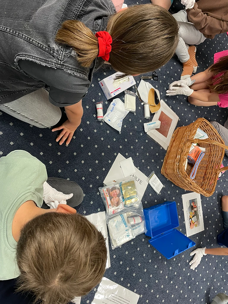 Kinder schauen in den Inhalt eines Erste Hilfe Kastens.