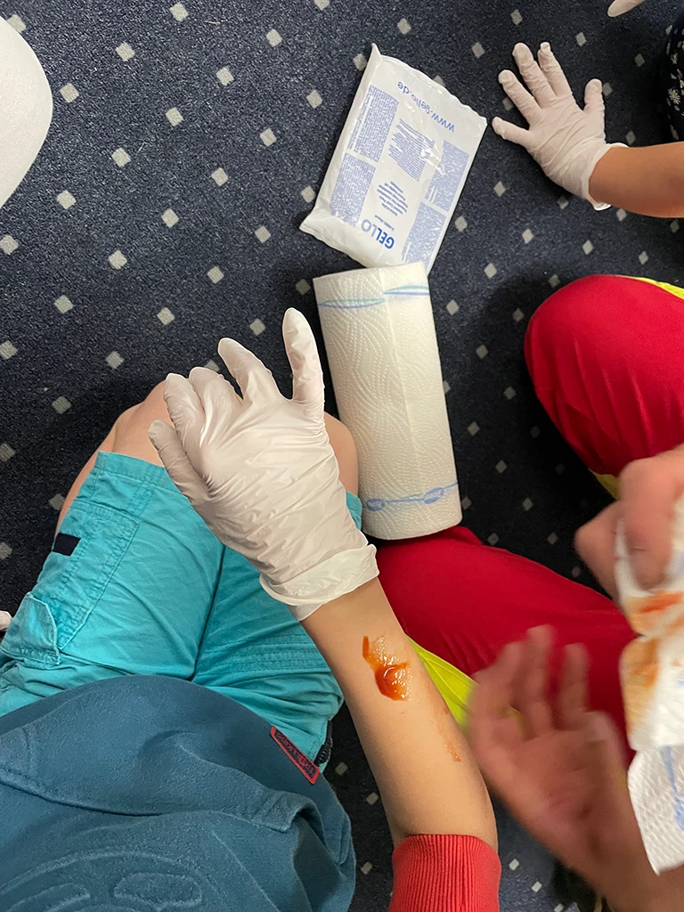 Kind simuliert mit Ketchup eine Wunde auf dem Arm.