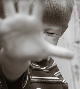 Ein kleiner Junge hat die Hand vor dem gesicht und sagt damit eindeutig "Nein"