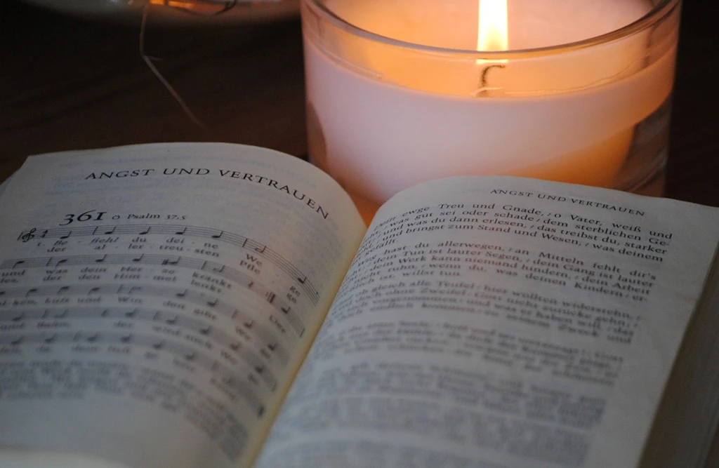 Aufgeschlagenes Evangelisches Gesangbuch mit Nummer 361; dahinter brennt eine weiße Kerze.